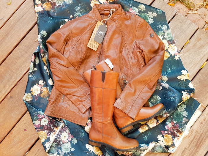 braune Lederjacke und Stiefel auf geblümtem Stoff, die Mode des Herbstes 2018